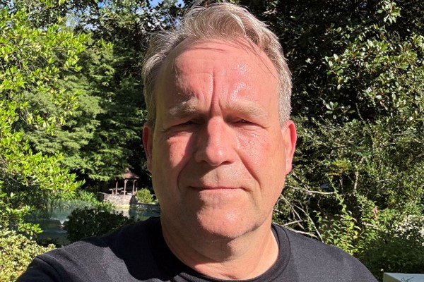 Person in garden under sunlight, surrounded by greenery.