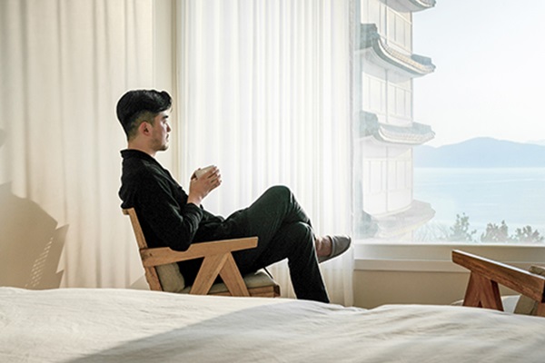 Person sipping coffee, enjoying ocean view from window.
