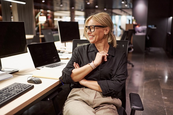 Smiling woman sitting at desk in modern office.