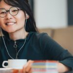 Persona sonriente con auriculares junto a una taza.