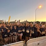 Happy marathon runners posing at sunset.