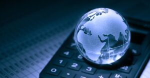 Glass globe on calculator, financial data background.